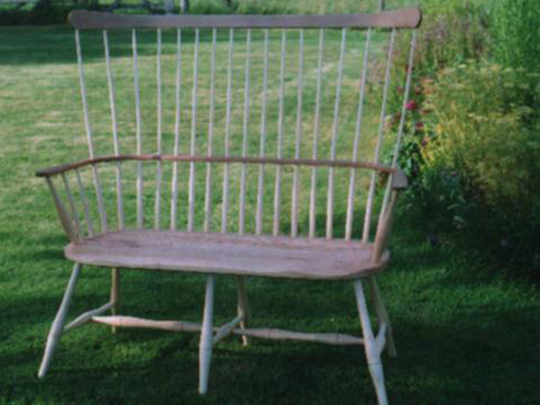 Handmade shawl back two seater settee made from local timber, shown outdoors.